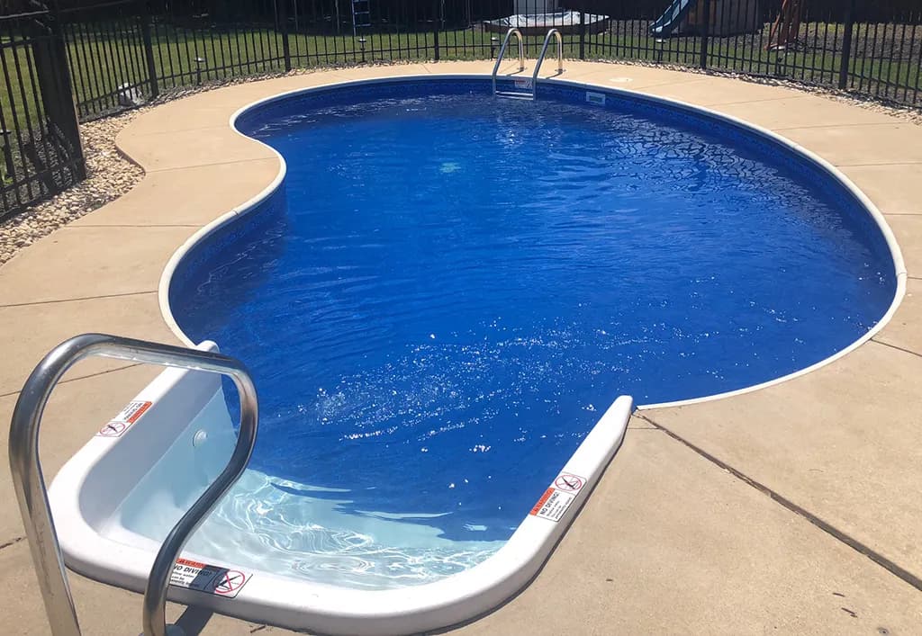 Completed luxury pool with elegant stone coping and clear blue water in a residential backyard