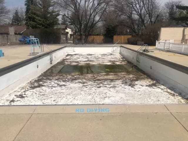 Custom pool at dusk with landscape lighting and a water feature running